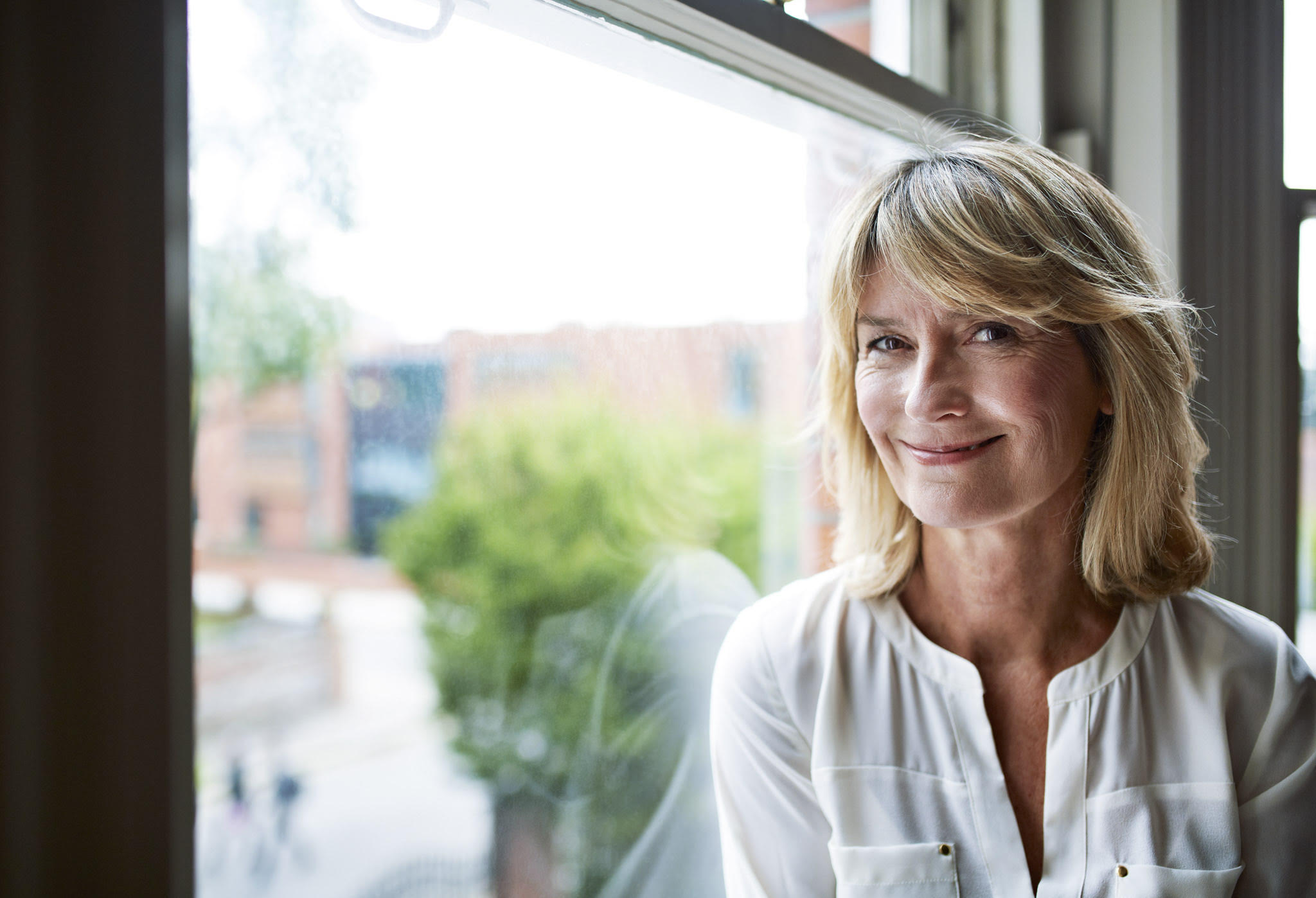 Portrait of a smiling mature woman sitting by a window at home